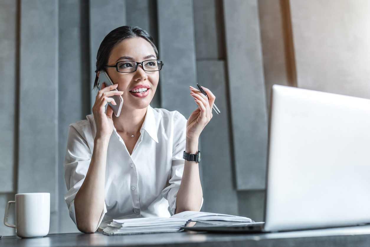 Businessperson on phone in front of laptop | line of credit small business Fundid