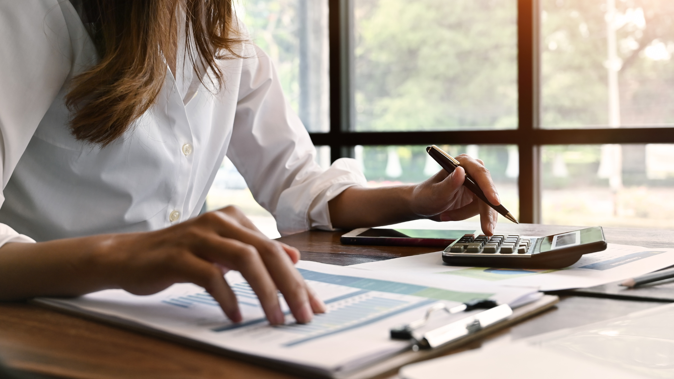 How to Keep Track of Finances for a Small Business | Woman at a desk with papers