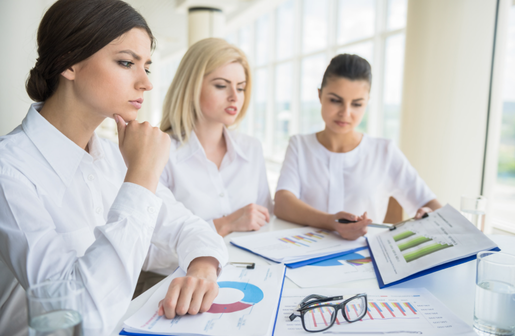 Three women looking at graphs. 