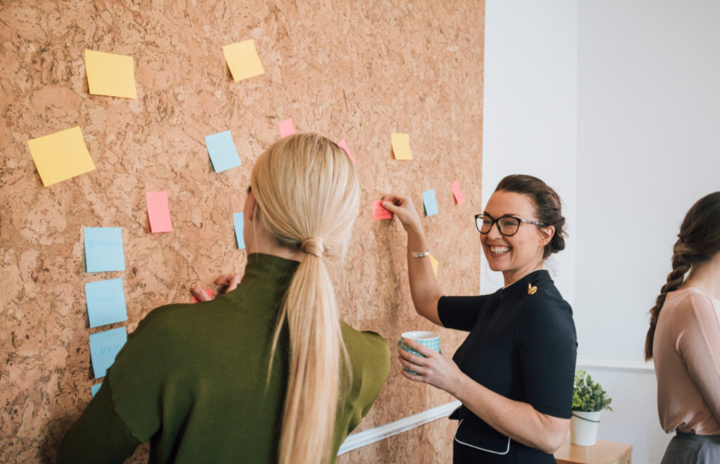 Woman placing notes on a bulletin board.