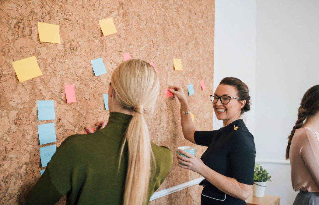 Woman placing notes on a bulletin board. 