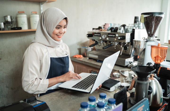 Woman working on a laptop at a coffee shop.