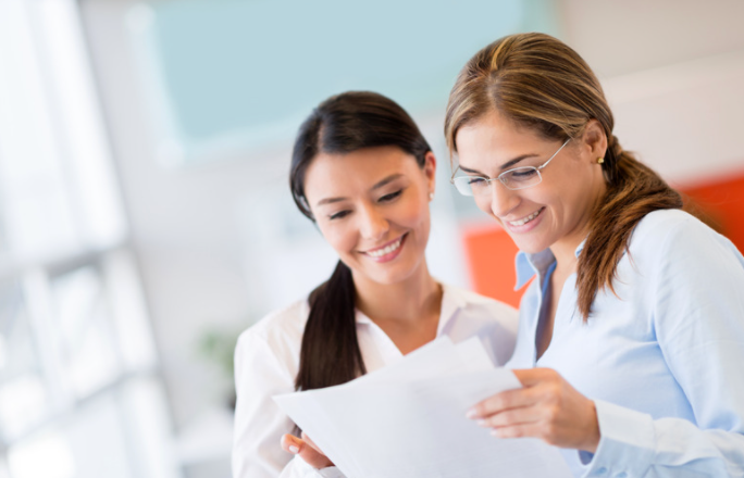 Two women reviewing notes.