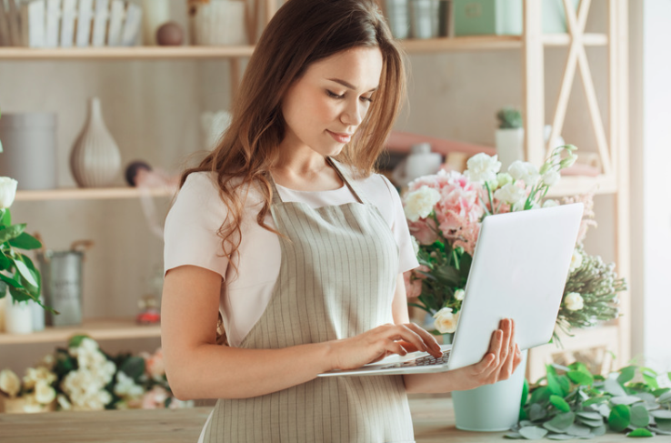 Woman working on a laptop in a flower shop.