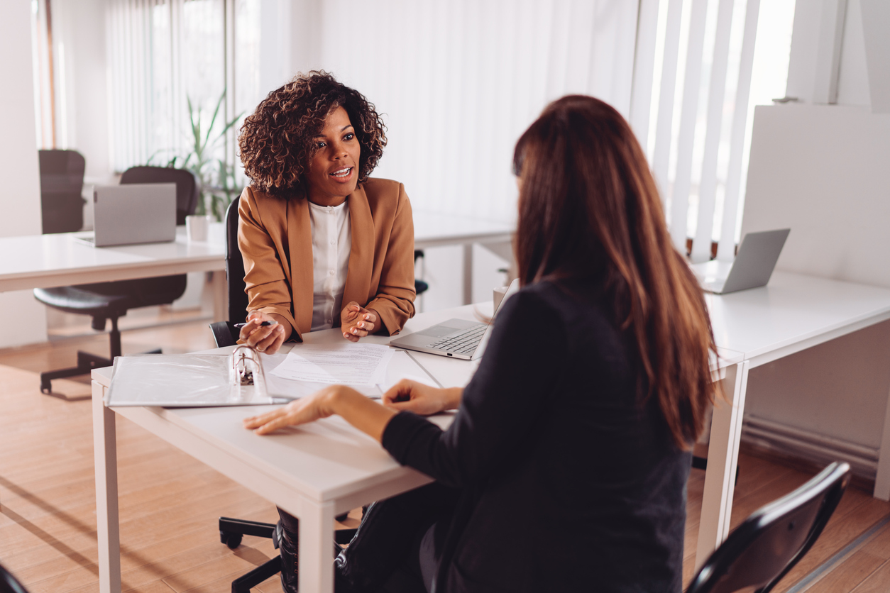 Two women in a meeting across the table from each other. 