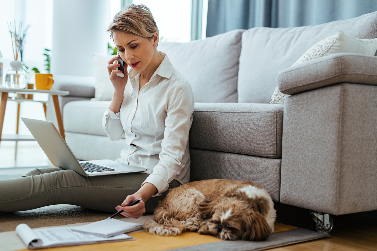 Woman working on a laptop sitting on the floor. 